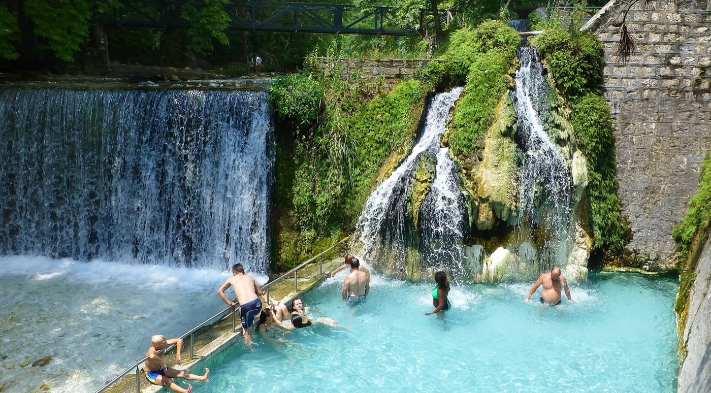 Steaming open-air thermal pools at Pozar with stone bridges