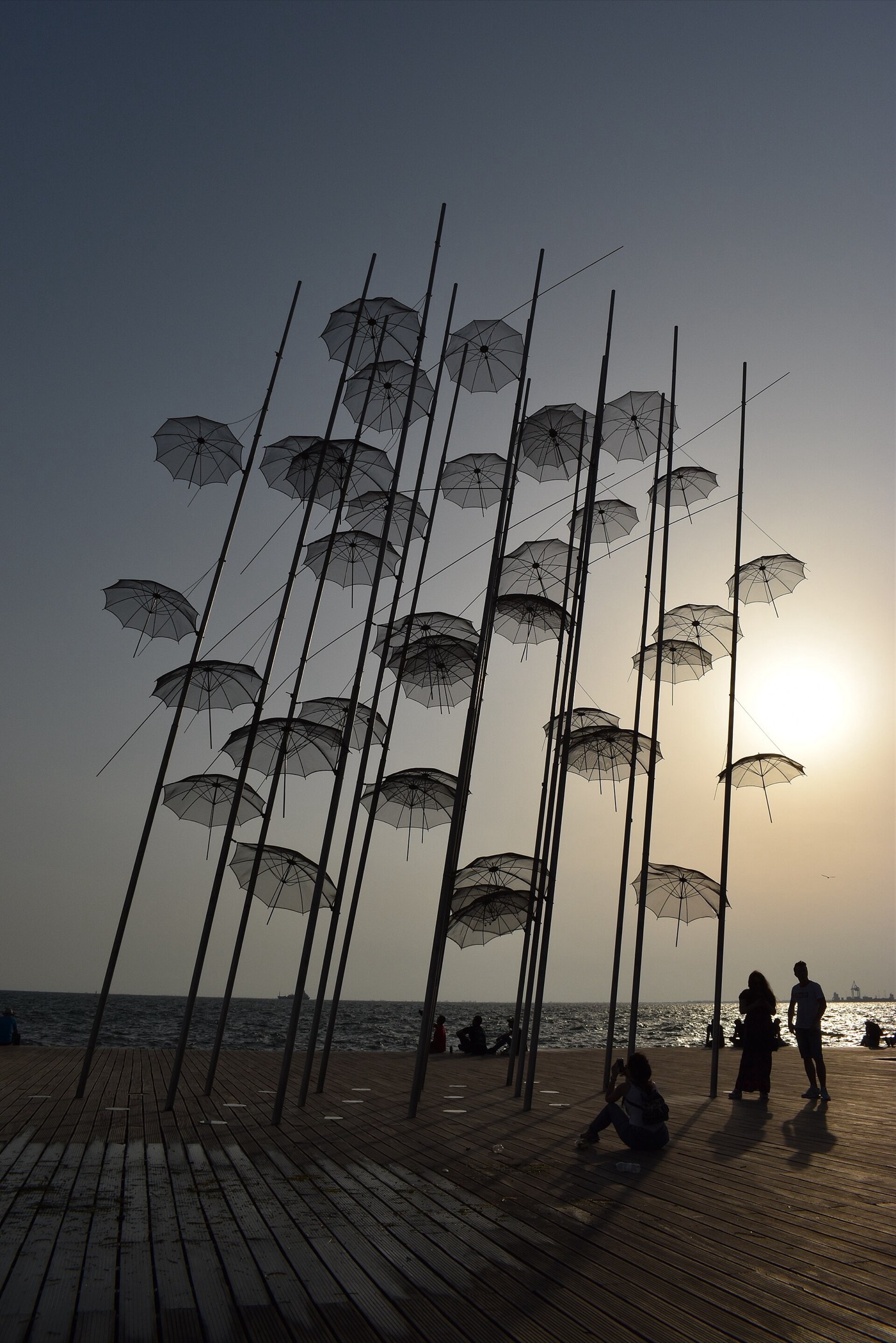 The Umbrellas sculpture by George Zongolopoulos silhouetted against the sunset on the seafront